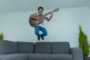 mexican boy jumping off the sofa and playing the guitar