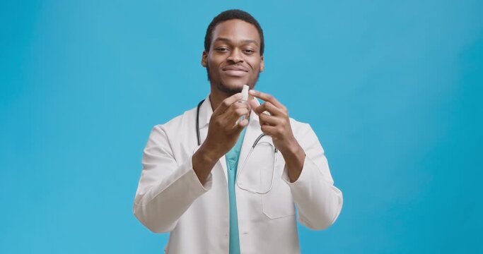 Hands disinfection. Studio shot of black medical doctor spraying antiseptic on hands and rubbing them