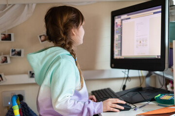 Child using a computer at home to do school work in a bedroom during school closures due to covid-19 pandemic
