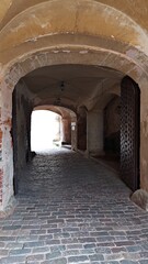 Long arch under the wall of the old castle and a paved stone road to drive through