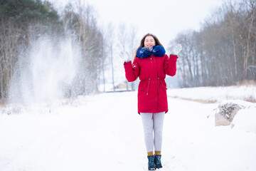 Young woman in red coat throwing snow