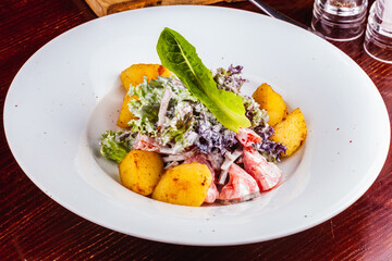 Salad with baked potatoes, tomatoes, lettuce and beef tongue on white plate