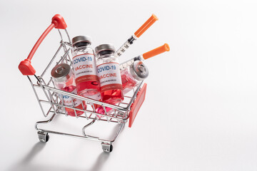 Wire shopping cart with vaccine vials bottles and syringes for vaccination against COVID-19...