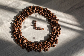 Coffee beans in the shape of a watch. Gray background.
