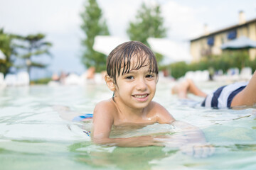 Cute little boy kid child splashing in swimming pool having fun leisure activity