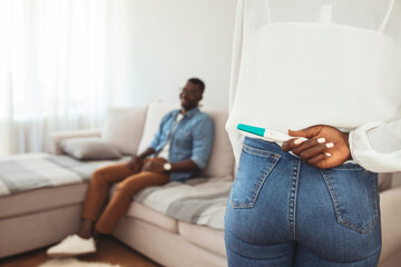 Close up of woman hands hiding pregnancy test from man. Woman hiding positive pregnancy test from...