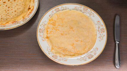Crepes, thin pancakes on a white plate. brown background