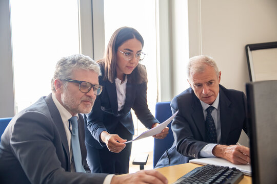 Investors and trade expert looking at monitor together. Young businesswoman and two mature colleagues staring at display. Medium shot. Business and expertise concept