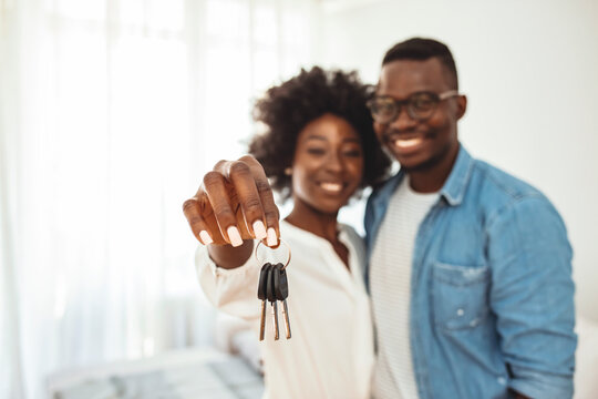 Portrait of young couple feeling happy about buying a new house.. Young couple holding up new house key. Super excited about our new home! Couple holding a house key in their new home