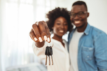 Young smiling African-American couple showing keys to new home hugging looking at camera. Portrait...
