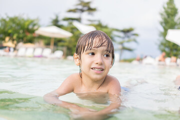 Fototapeta na wymiar Cute little boy kid child splashing in swimming pool having fun leisure activity