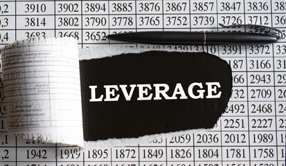 LEVERAGE is the word behind torn office paper with numbers and a black pen.