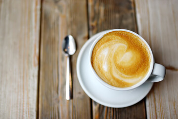 A cup of fresh cappuccino coffee on a wooden table in a cafe or restaurant. Coffee break.