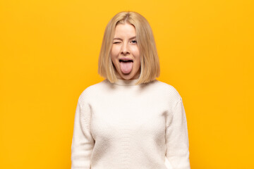 blonde woman with cheerful, carefree, rebellious attitude, joking and sticking tongue out, having...
