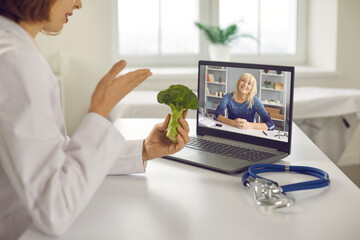 Online wellness consultation via video call: Doctor, dietitian or nutritionist sitting at laptop,...