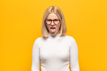 blonde woman feeling disgusted and irritated, sticking tongue out, disliking something nasty and...