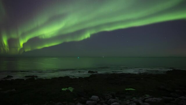 Aurora borealis reflecting over ovean waves Iceland timelapse