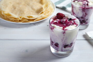 Delicious vanilla ice cream dessert with berry sauce next to delicious pancakes