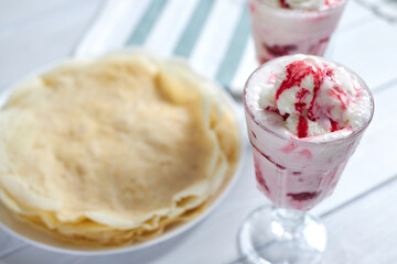 Delicious vanilla ice cream dessert with raspberry sauce next to delicious pancakes