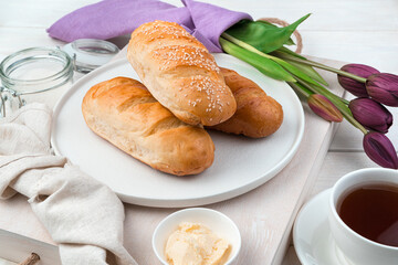 Three fresh loaves on a festive background with tea and tulips. Side view. The concept of festive culinary backgrounds, spring.