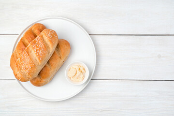 Bread and butter in a flat plate on a white wooden background. Top view with copy space. The concept of a Culinary background.