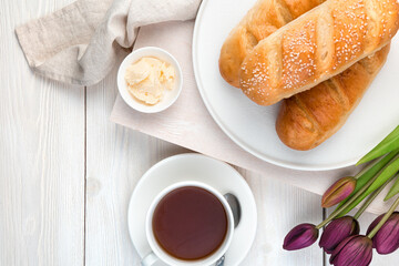 Tea, fresh bread and flowers on a light background. Top view with copy space. The concept of festive culinary backgrounds.