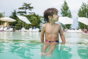 Obraz premium Young boy kid child splashing in swimming pool having fun leisure activity