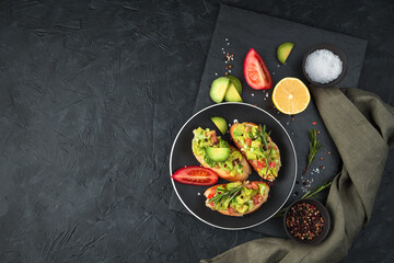 Three sandwiches with avocado, tomatoes and lemon on a black background. Top view, with space to copy. The concept of healthy eating.