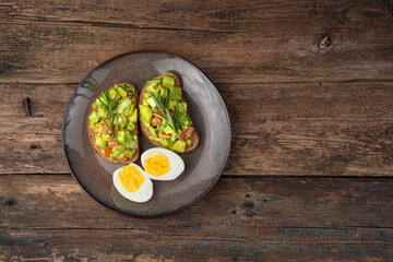 Two avocado sandwiches and sliced boiled eggs on a wooden background. Top view, with space to copy. The concept of healthy eating.