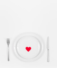 Fototapeta na wymiar Romantic dinner table. Festive table setting with a red heart in a plate on a white background. Love concept. Space for text. Top view, flat lay.