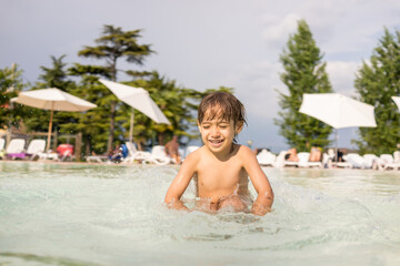 Cute little boy kid child splashing in swimming pool having fun leisure activity