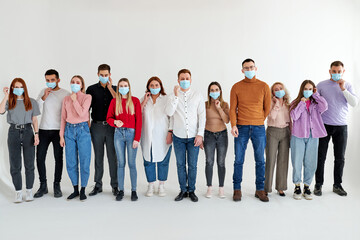 people wearing medical face mask, stand in a row posing looking at camera, isolated over white studio background. global society. disease epidemic, coronavirus infection concept