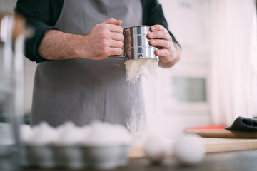 A male chef prepares dough at home in the kitchen