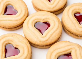 Background from cookies. Cookie Hearts shape Red jam or strawberry jelly inside biscuit cookie. Homemade baking. Sweet bakery. Top view on white background.