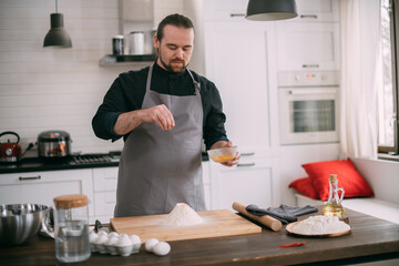 A male chef prepares dough at home in the kitchen