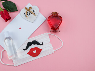 The letter, heart, rose, mask, mustache, smile and disinfectant lie on the left against a pink background with space for text on the right, top view.