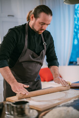 A male chef prepares noodles at home in the kitchen.