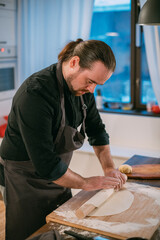 A male chef prepares noodles at home in the kitchen.