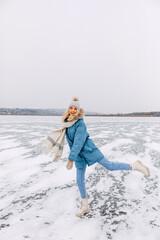 Happy young woman skating on ice on a frozen lake on a cold winter day.