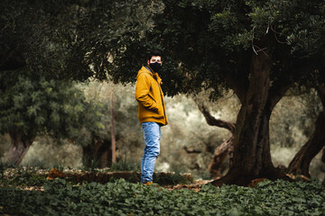 Young man with face mask in the middle of a green forest