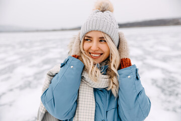 Closeup portrait of a cheerful young blonde woman on cold winter day, smiling.
