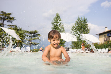 Cute little boy kid child splashing in swimming pool having fun leisure activity