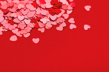Beautiful festive background with red metallic heart shaped confetti. Valentine's day background. Copy space for your text. Selective focus.