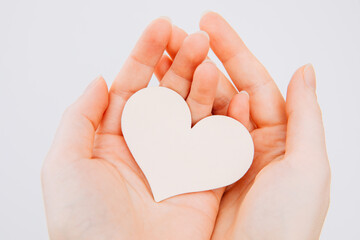 Fototapeta premium hands holding heart. Woman holds a white wooden heart in her hands. Valentine's day. Give away a heart. Tender heart.