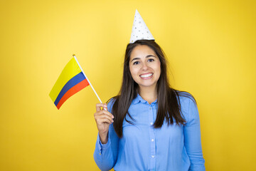 Young caucasian woman wearing a birthday hat over isolated yellow background smiling and holding a...
