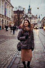 Naklejka premium beautiful brunette walking the city streets in winter. holiday mood. winter and rest. walks during quarantine