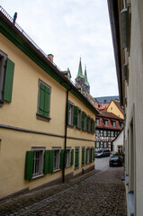Fototapeta na wymiar View into a narrow alley of the World Heritage city of Bamberg with the famous Bamberg Cathedral in the background. High quality photo