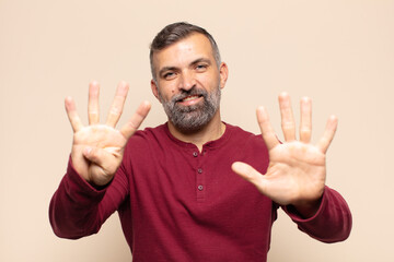 adult handsome man smiling and looking friendly, showing number nine or ninth with hand forward,...