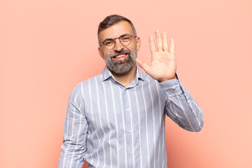 adult handsome man smiling happily and cheerfully, waving hand, welcoming and greeting you, or saying goodbye © kues1