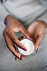 dark skinned female hand holding moisturizer in hand, 
